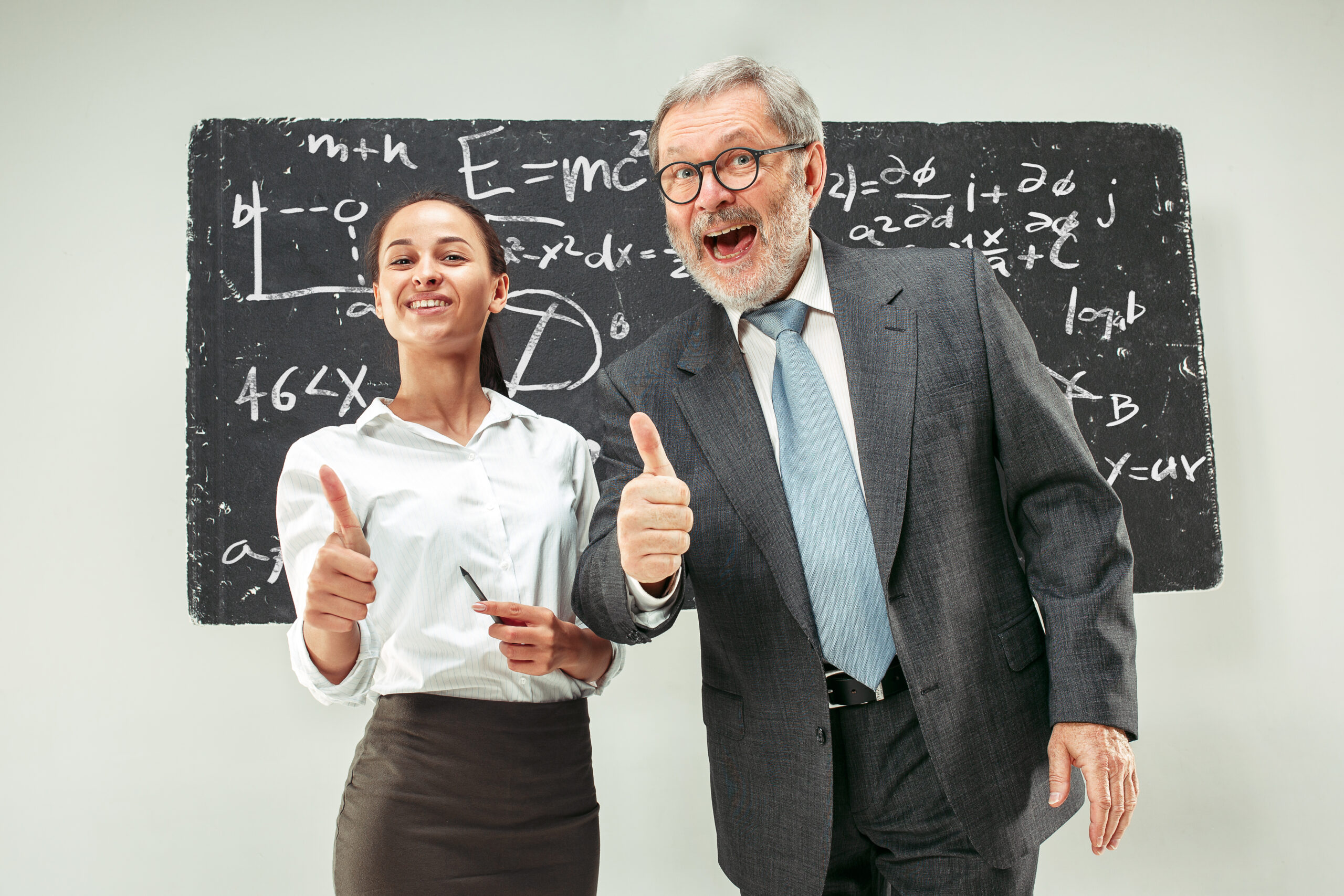 Male senior professor and young female student against chalkboard in classroom. Human emotions concept. Caucasian models. Education, college, university, lecture, school, learning concepts